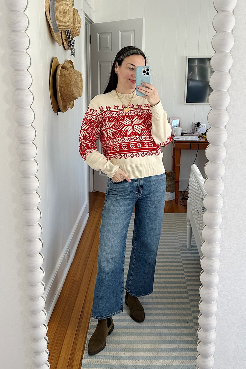 Carly Riordan taking a mirror selfie wearing a red fair isle sweater and jeans.