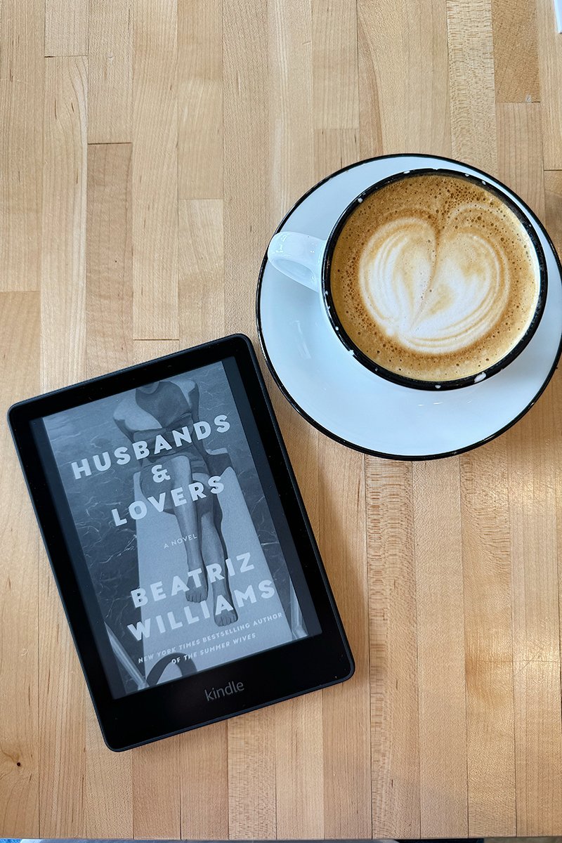 A kindle featuring Husbands and Lovers with a cappuccino